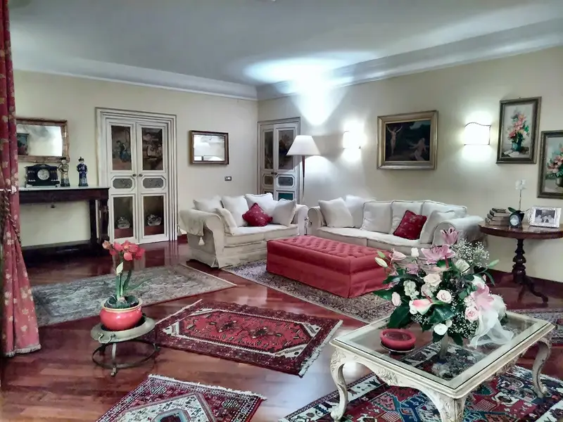 Salotto con divani bianchi, pouf rosso e fiori freschi (ingrandisci)